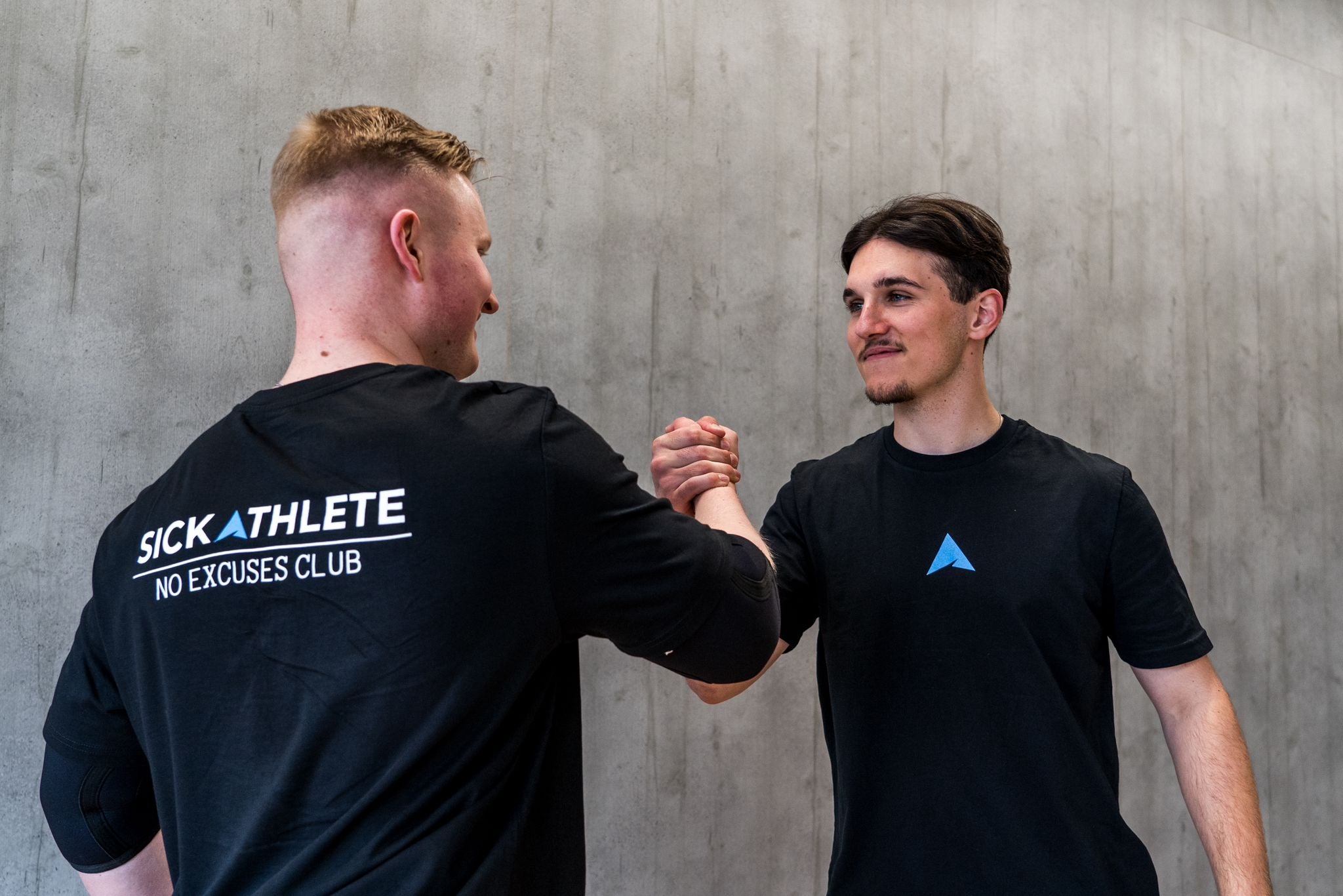 Zwei Athleten geben sich im Gym einen Handschlag, auf dem Rücken ist das SICKATHLETE logo