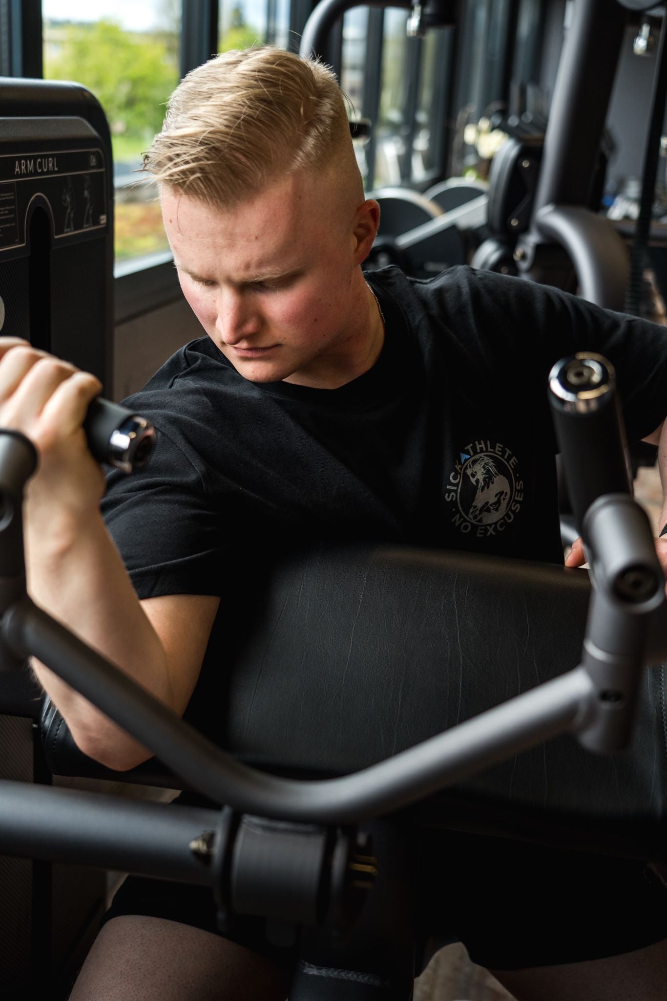 Bodybuilder Trainiert im Gym seinen Bizeps und trägt ein SICKATHLETE T-Shirt