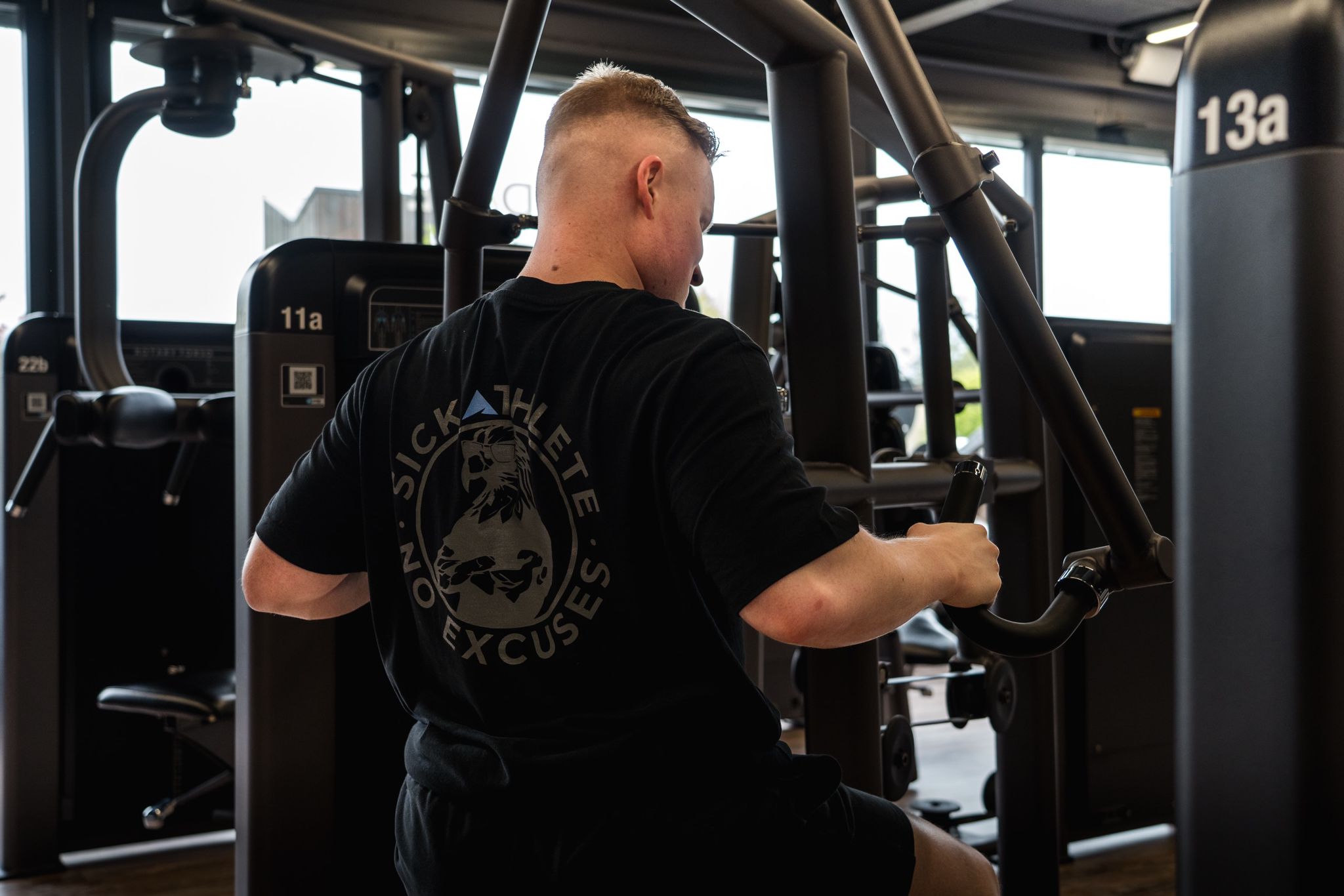 Muskulöser Athlet trainiert im Gym seinen Rücken und trägt dabei sein SICKATHLETE Purpose T-shirt auf dem ein Adler zu sehen ist.